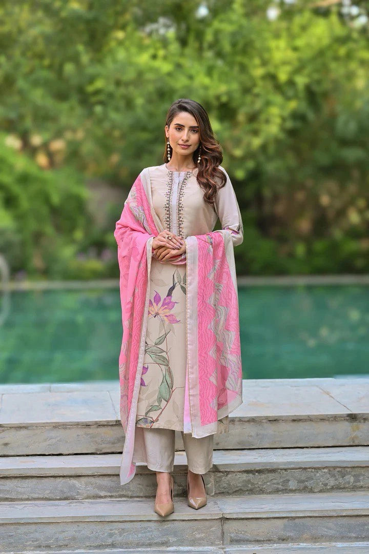Woman in a traditional outfit with pink dupatta standing outdoors.